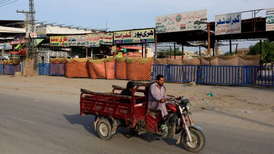 Un hombre viaja en triciclo, pasando junto a terminales de autobuses cerradas, ​​tras la suspensi&oacute;n del transporte y el cierre de mercados por motivos de seguridad en Islamabad