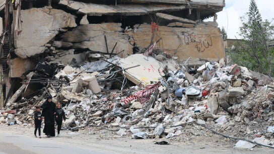 Personas caminan junto a los escombros de un edificio da&ntilde;ado por un ataque a&eacute;reo israel&iacute; en la aldea de Jibchit, al sur del L&iacute;bano