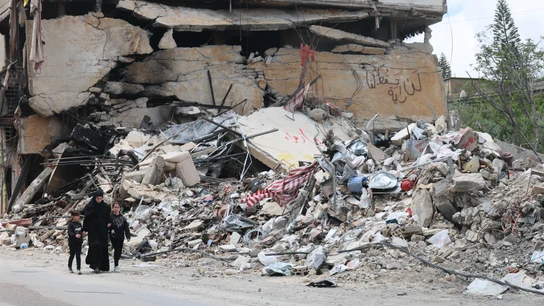 Personas caminan junto a los escombros de un edificio dañado por un ataque aéreo israelí en la aldea de Jibchit, al sur del Líbano Personas caminan junto a los escombros de un edificio dañado por un ataque aéreo israelí en la aldea de Jibchit, al sur del Líbano