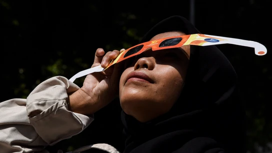Una mujer viendo un eclipse solar con gafas Una mujer viendo un eclipse solar con gafas