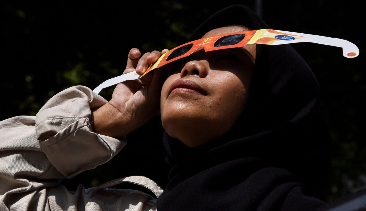 Una mujer viendo un eclipse solar con gafas