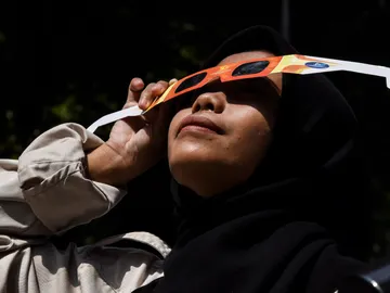 Una mujer viendo un eclipse solar con gafas Una mujer viendo un eclipse solar con gafas