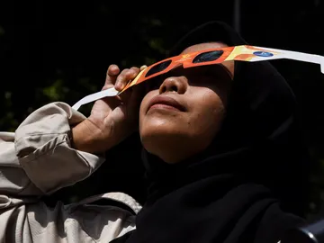 Una mujer viendo un eclipse solar con gafas Una mujer viendo un eclipse solar con gafas