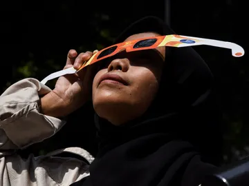 Una mujer viendo un eclipse solar con gafas Una mujer viendo un eclipse solar con gafas