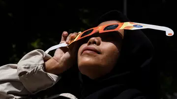 Una mujer viendo un eclipse solar con gafas Una mujer viendo un eclipse solar con gafas