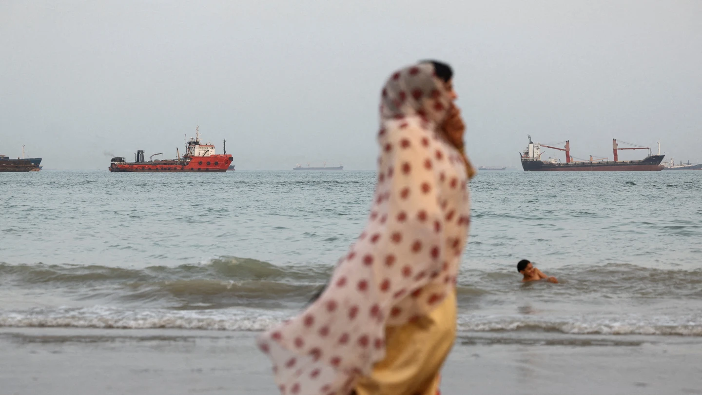 Personas caminan por la playa, con embarcaciones visibles en el estrecho de Ormuz cerca de la playa de Bandar Abbas, Irán Personas caminan por la playa, con embarcaciones visibles en el estrecho de Ormuz cerca de la playa de Bandar Abbas, Irán