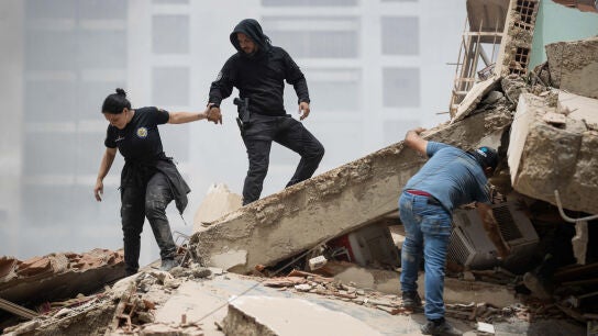 Personas caminan entre escombros de edificios derrumbados este jueves, en La Guaira. 