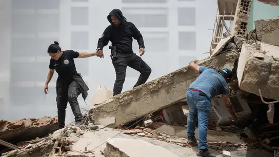 Personas caminan entre escombros de edificios derrumbados este jueves, en La Guaira. Personas caminan entre escombros de edificios derrumbados este jueves, en La Guaira.