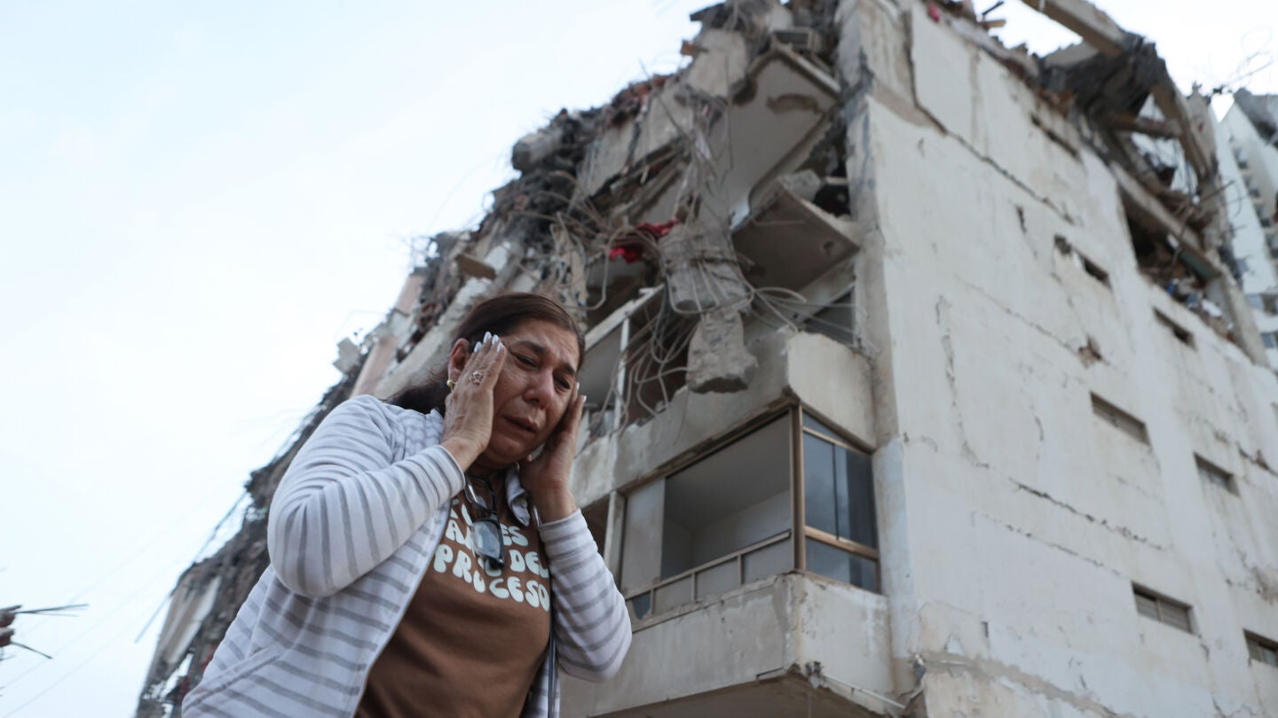 Una mujer camina entre los escombros de un edificio derrumbado por los terremotos en Venezuela
