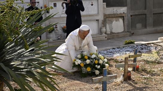 El papa Le&oacute;n XIV deposita una ofrenda floral en una tumba durante una parada en el cementerio local de Lampedusa