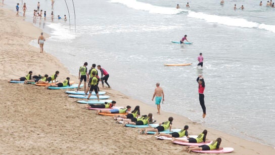 Un grupo de surfistas se prepara para entrar al agua en la playa de la Zurriola de San Sebasti&aacute;n.
