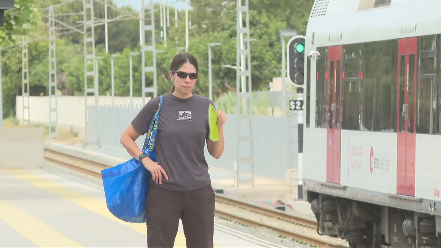 Mujer abanicándose al lado de un tren Mujer abanicándose al lado de un tren