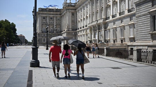 Imagen de archivo. Varias personas protegi&eacute;ndose del sol frente al Palacio Real en Madrid.