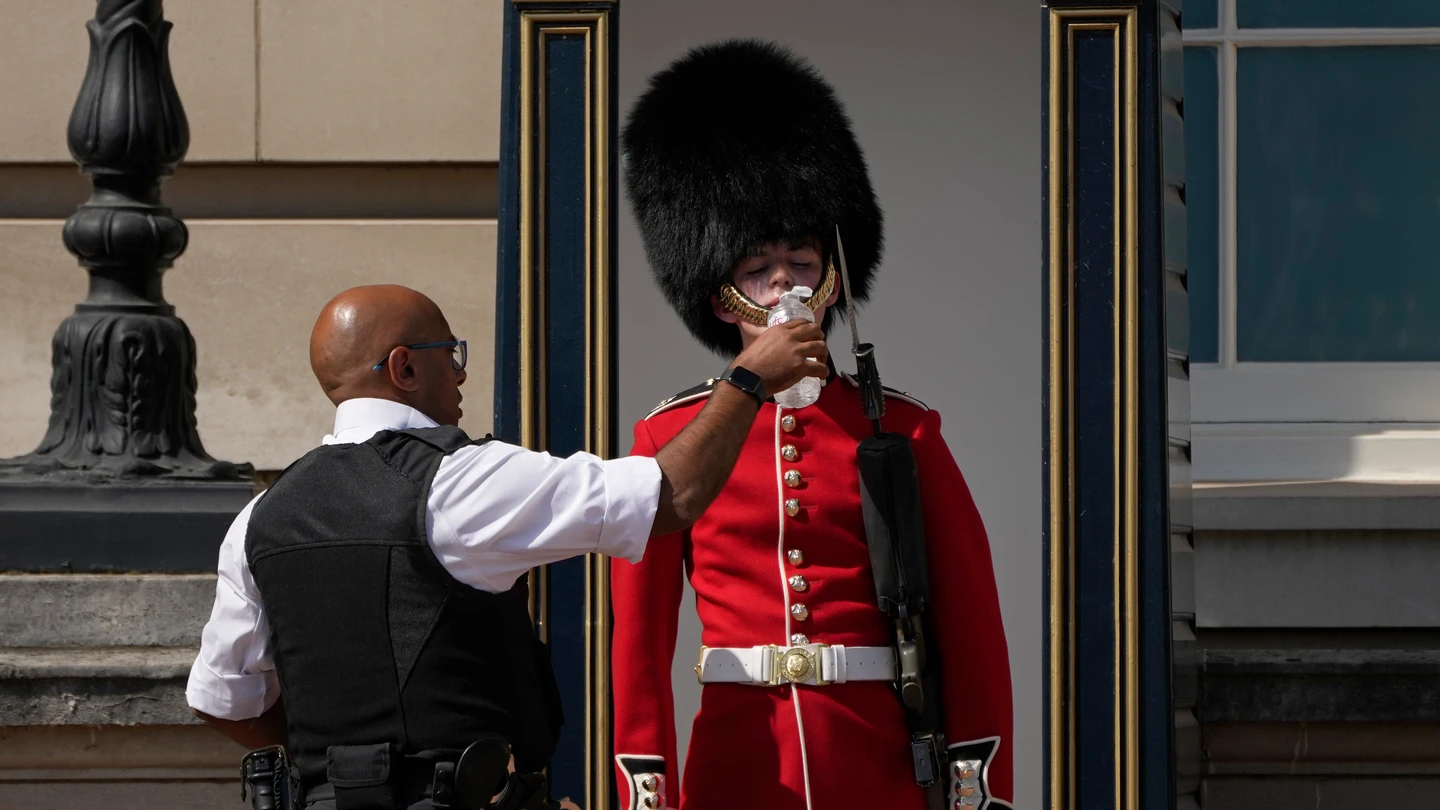 Un agente de policía da agua a un soldado británico que está de guardia frente al Palacio de Buckingham, durante una jornada de calor en Londres. Un agente de policía da agua a un soldado británico que está de guardia frente al Palacio de Buckingham, durante una jornada de calor en Londres.