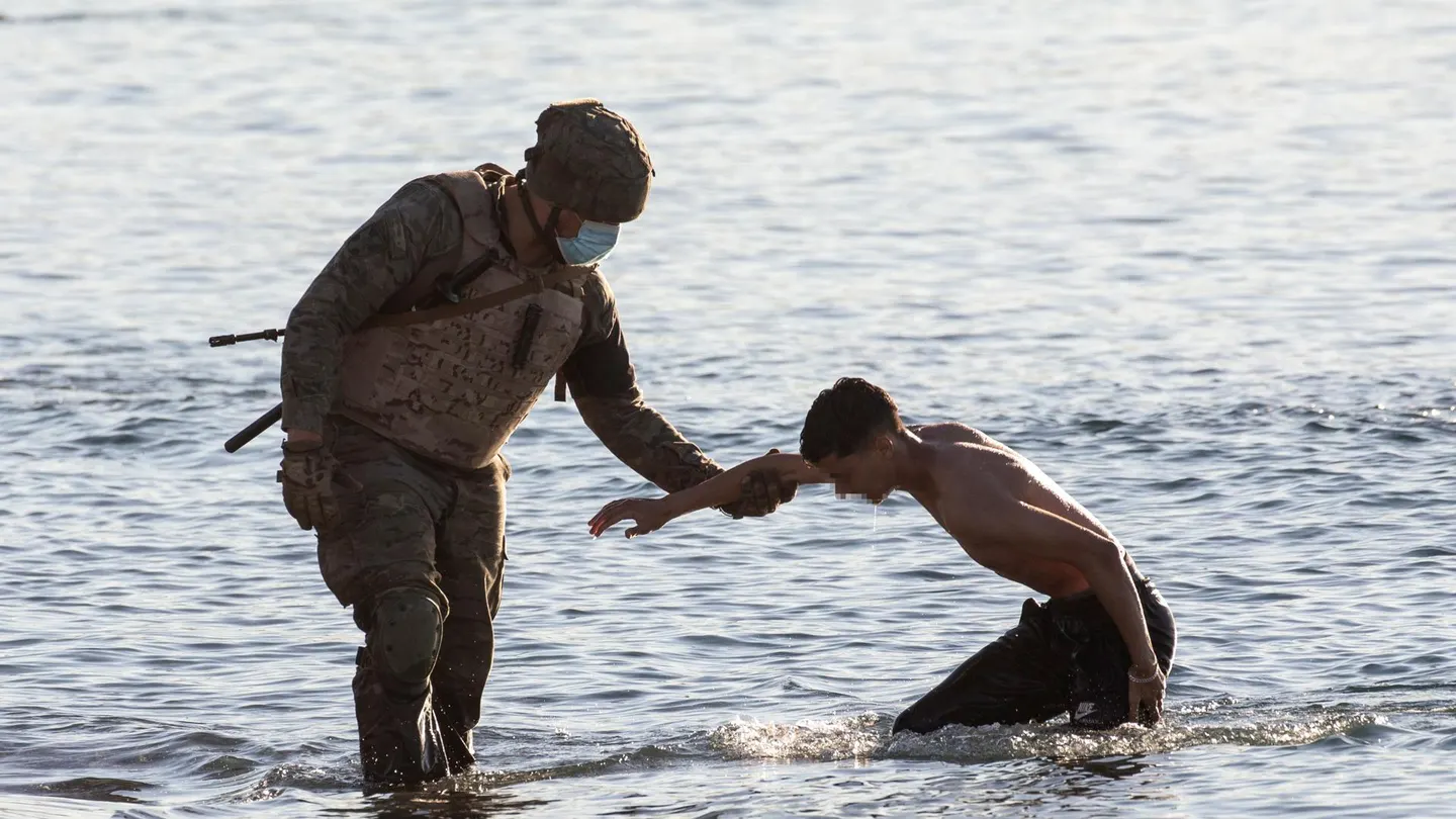 Un soldado del ejército ayuda a un inmigrante a su llegada a la playa de El Tarajal en Ceuta. Un soldado del ejército ayuda a un inmigrante a su llegada a la playa de El Tarajal en Ceuta.
