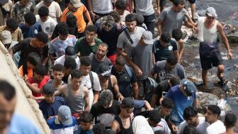 Varias personas caminan por la playa tras intentar cruzar desde la localidad marroqu&iacute; de Fnideq, situada al norte del pa&iacute;s, hasta Ceuta. 