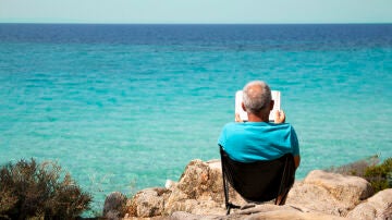 Persona leyendo junto al mar