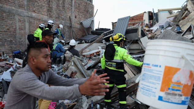 Personal de emergencia y otras personas trabajan en el lugar de un edificio da&ntilde;ado tras un terremoto en Pereira, Colombia