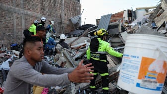 Personal de emergencia y otras personas trabajan en el lugar de un edificio da&ntilde;ado tras un terremoto en Pereira, Colombia