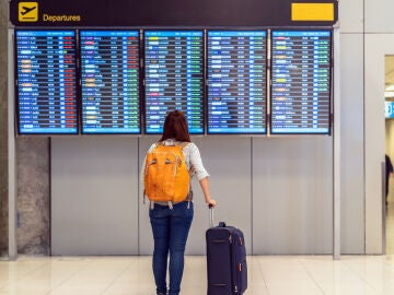persona mirando panel de salidas aeropuerto