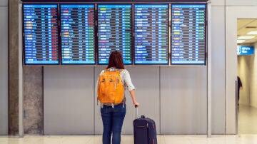persona mirando panel de salidas aeropuerto