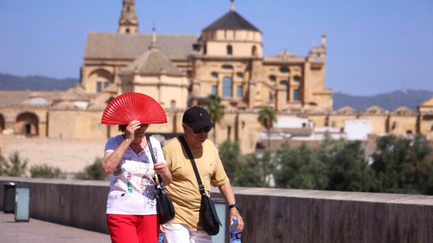 Una viandante se protege del sol con un abanico en C&oacute;rdoba 