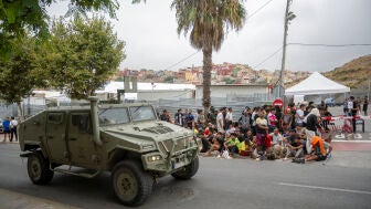 Un blindado militar pasa junto a una cola de inmigrantes, a 1 de septiembre de 2026, en Ceuta (Espa&ntilde;a).