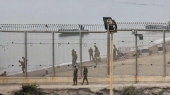 Dos soldados espa&ntilde;oles y en la parte marroqu&iacute; de la playa autoridades del pa&iacute;s vecino montan guardia en el espig&oacute;n del Tarajal 