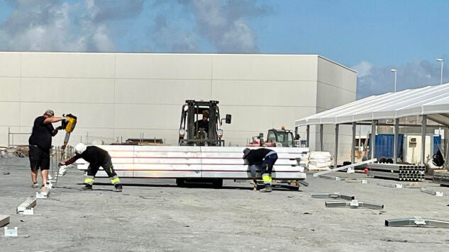 Operarios preparan una carpa de grandes dimensiones en muelle Poniente del puerto de Ceuta que tendr&aacute; una capacidad para alojar a mil migrantes. 