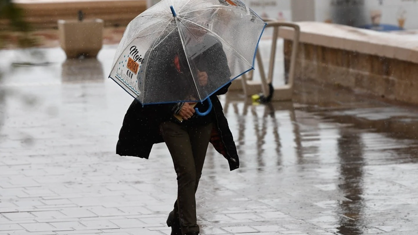 Una mujer se resguarda de la lluvia Una mujer se resguarda de la lluvia