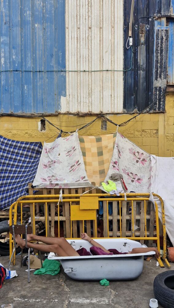 Un migrante duerme en una bañera en un campamento improvisado en Ceuta.