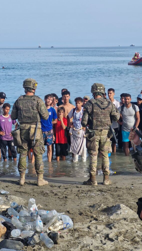 Militares españoles en la orilla frente a un grupo de migrantes recién llegados a nado a Ceuta. 