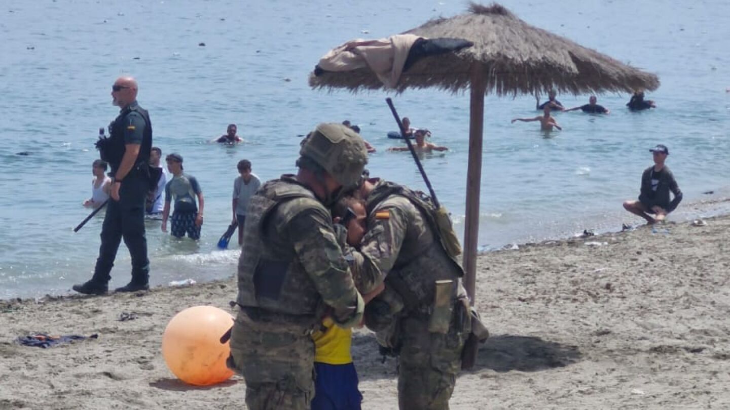 Dos militares espa&ntilde;oles abrazan a un menor reci&eacute;n llegado a Ceuta desde Marruecos.