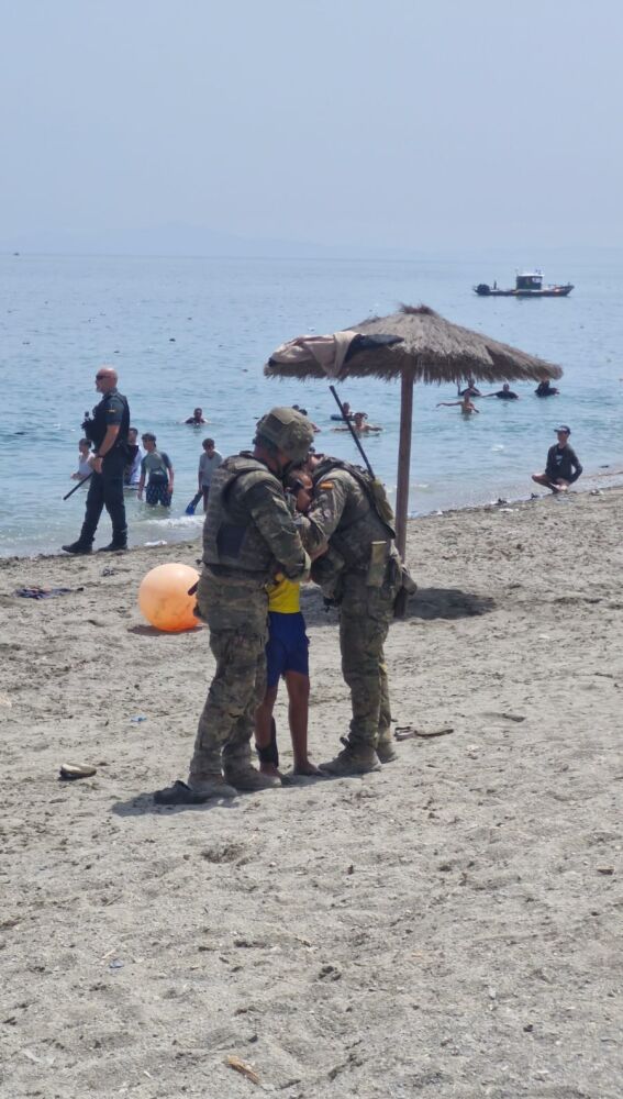 Dos militares españoles abrazan a un menor recién llegado a Ceuta desde Marruecos.