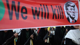 Mujeres miembros de las fuerzas de la milicia iran&iacute; portan una pancarta contra el presidente estadounidense, Donald Trump, durante una marcha militar en Teher&aacute;n.