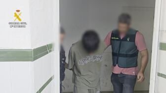 Un agente de la Guardia Civil, con uno de los detenidos.