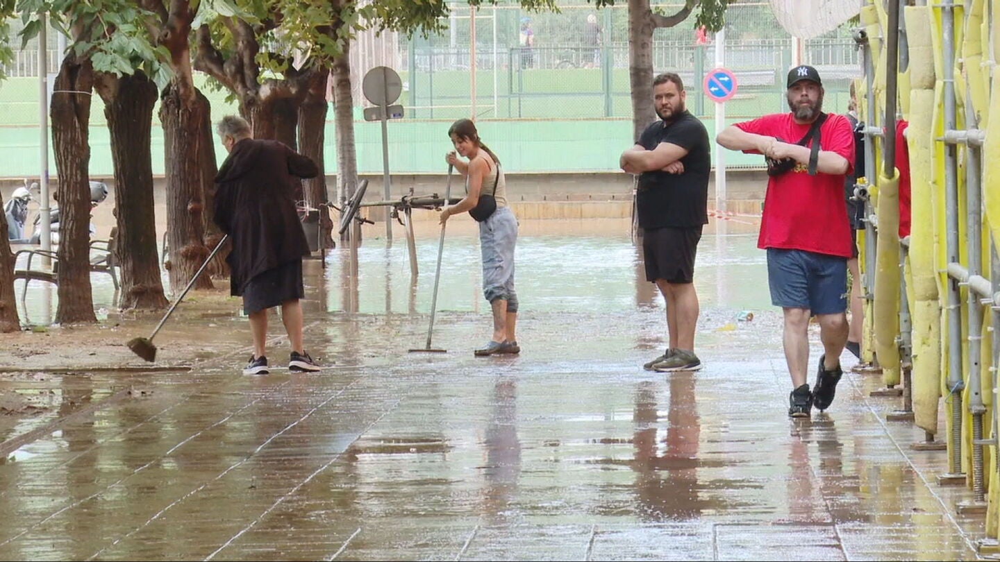 Ciudadanos limpian las calles tras el paso del temporal por Barcelona. 