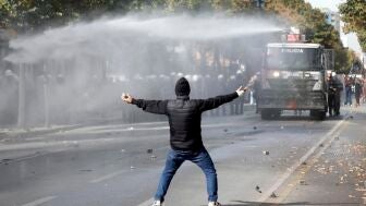 Un manifestante, frente a un veh&iacute;culo de la Polic&iacute;a de Albania