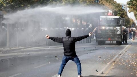 Un manifestante, frente a un veh&iacute;culo de la Polic&iacute;a de Albania