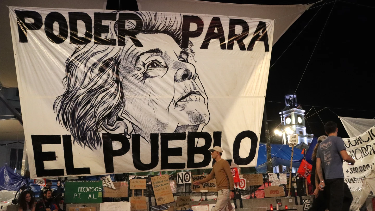Fotografía que muestra una pancarta con el rostro de Maricarmen en la acampada por la situación de la vivienda Fotografía que muestra una pancarta con el rostro de Maricarmen en la acampada por la situación de la vivienda