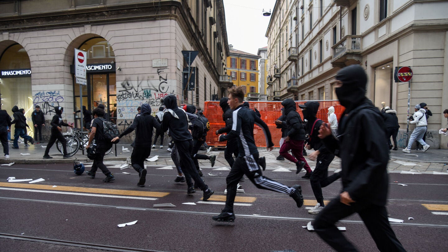 Manifestantes corren por una calle llena de escombros durante una protesta por el estado de los servicios p&uacute;blicos y el aumento del costo de vida en Mil&aacute;n, Italia