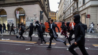 Manifestantes corren por una calle llena de escombros durante una protesta por el estado de los servicios p&uacute;blicos y el aumento del costo de vida en Mil&aacute;n, Italia