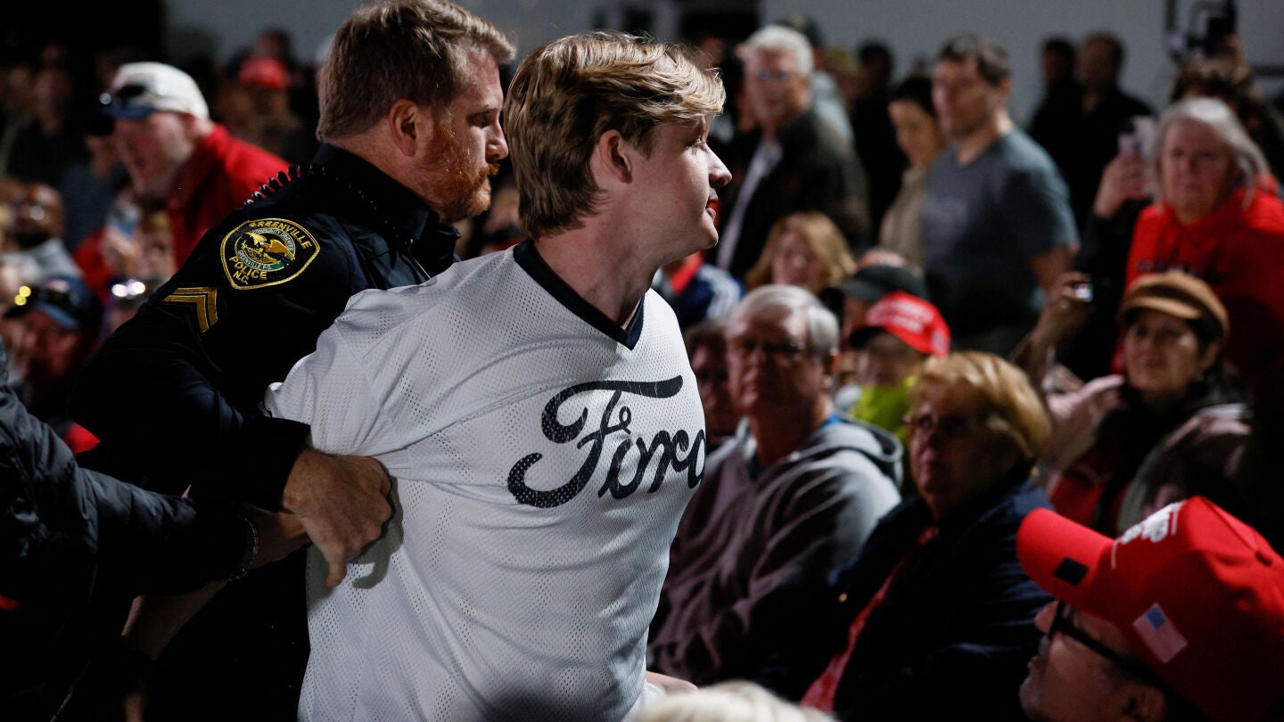 Un manifestante es retirado mientras Donald Trump habla durante un mitin en el aeropuerto de Pitt-Greenville, Carolina del Norte.