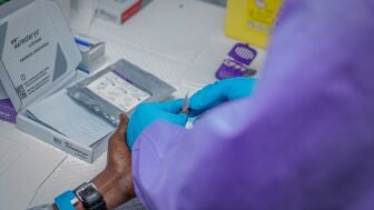 Imagen de archivo. Un trabajador sanitario realiza un control previo a un voluntario que participa en el ensayo cl&iacute;nico de una vacuna contra el virus del &eacute;bola