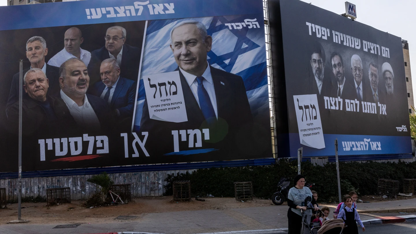 Varias personas caminan junto a una pancarta de campaña del partido Likud de Netanyahu antes de las elecciones parlamentarias en Israel Varias personas caminan junto a una pancarta de campaña del partido Likud de Netanyahu antes de las elecciones parlamentarias en Israel