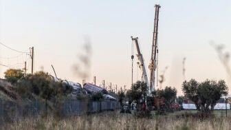 Los servicios de emergencia junto a maquinaria pesada trabajan en el lugar del accidente ferroviario un d&iacute;a despu&eacute;s del suceso